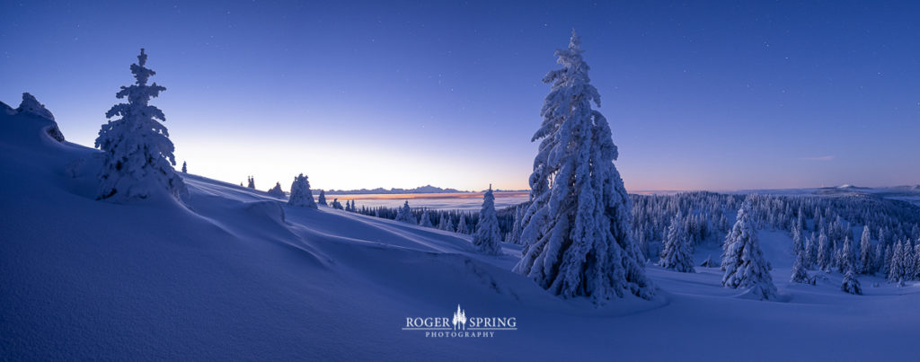 Winterlandschaft im Jura Schweiz mit verschneiten Bäumen bei Sonnenaufgang.